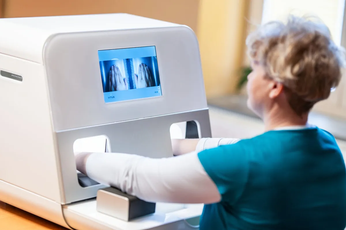 Kältetherapie-Gerät VITUS: Hände in den beleuchteten Behandlungsöffnungen, Display zeigt die laufende Sitzung